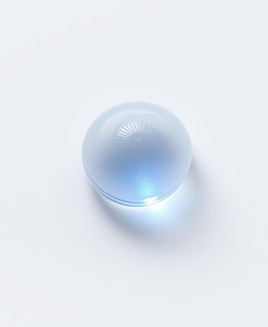 Clear gel droplet with blue refraction on a matte white surface